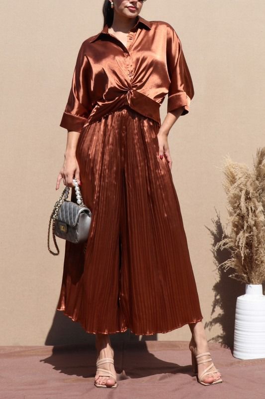 conjunto de seda con blusa de cuello y detalle de nudo al frente. Con pantalones plizados que leg